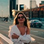 Young woman in casual attire posing confidently on a busy street in Buenos Aires during sunset.